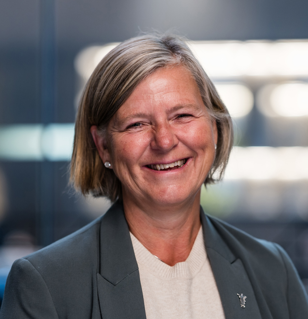 Bilde av president i Legeforeningen, Anne-Karin Rime. Hun har kort, lyst hår, perleøredobber og smiler. Hun har på seg grå-blå blazer med naturhvit genser inni.