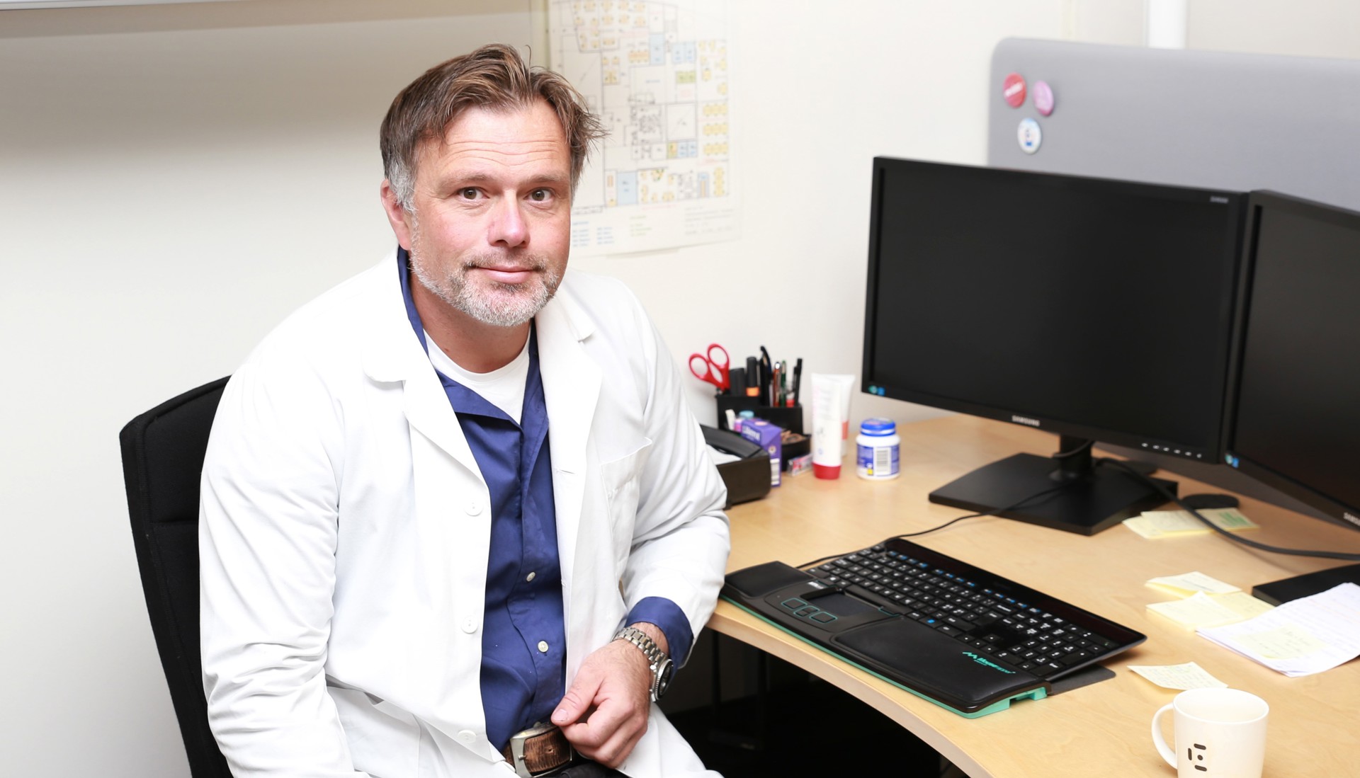Mannlig lege i hvit frakk ved kontorpult foran PC. Børge Lønnebakke Norberg foto Jarl-Stian Olsen  