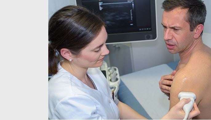 Bilde av lege som undersøker skulderen til en pasient.