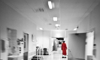Bilde av eldre dame som går bortover en korridor.