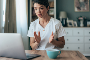 Lege som snakker med noen på en datamaskin. Foto: Istockphoto.com/filadendron