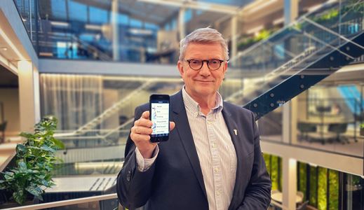 Geir Riise holder opp mobiltelefonen med A+ Legeforeningen-appen foran trappen i Legenes hus. Foto: Troy Gulbrandsen/Legeforeningen
