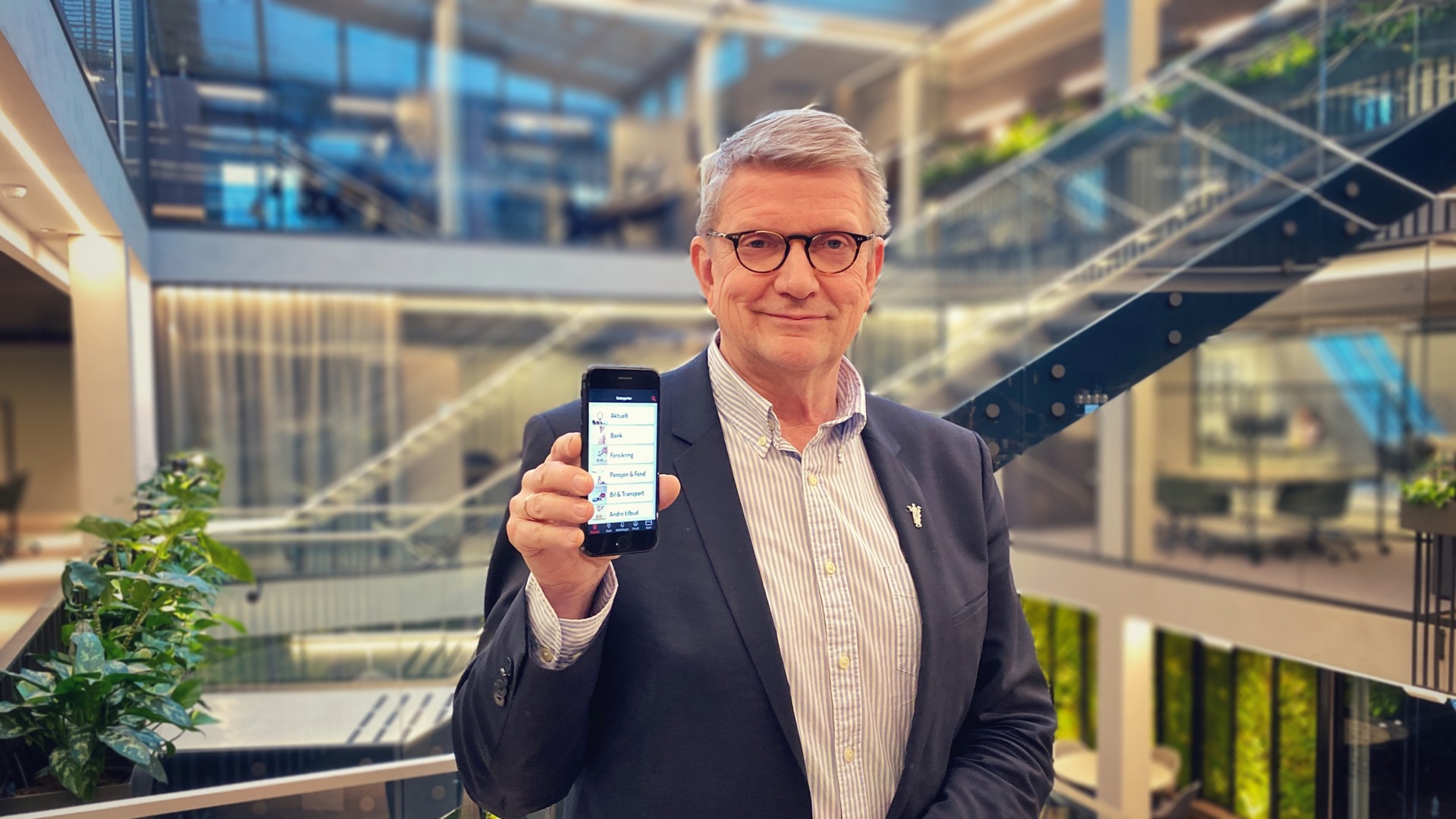 Geir Riise holder opp mobiltelefonen med A+ Legeforeningen-appen foran trappen i Legenes hus. Foto: Troy Gulbrandsen/Legeforeningen