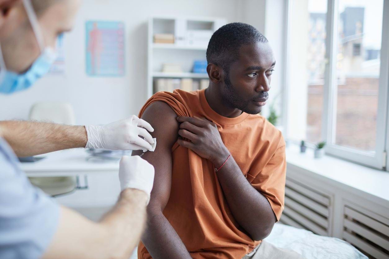 Mann får en vaksinesprøyte av helsepersonell. Foto: Istockphoto.com