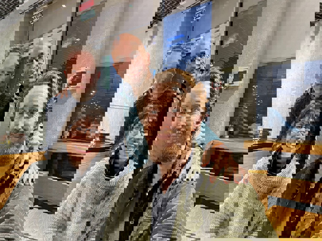 Fire smilende mennesker som holder rundt hverandre.