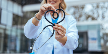 Kvinnelig helsepersonell som holder opp et stetoskop formet som et hjerte. Foto: Istockphoto.com/dragana991