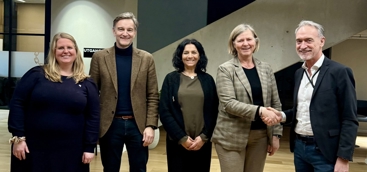 Fra venstre: Leder i YLF, Ingeborg Henriksen. Hun har langt, lyst hår og briller, og har på seg en mørkeblå kjole med lange ermer. Hun smiler. Ved siden av Henriksen står Bernhard Holthe, som sitter i Styret til Allmennlegeforeningen. Han har kortklippet, grått hår, brun dressjakke med mørkeblå polo inni, brunt belte og mørke jeans. Han smiler. Ved siden av Holthe står leder i LSA, Meera Grepp. Hun har mørkt, bølgete hår til skuldrene, har på seg mørk cardigan med grønn genser inni, samt mørke dressbukser. Hun smiler. Ved siden av Grepp står legepresident Anne-Karin Rime. Hun har lyst hår til haka, har på seg brun dressjakke med rutemønster og sort genser inni, brune dressbukser. Hun smiler, og tar mannen ved siden av seg i hånden. Han er Tor Arne Gangsø fra KS. Han har grått/hvitt hår og kort skjegg, har på seg mørkeblå dressjakke med hvit skjorte inni, og blå bukser. Han smiler.   