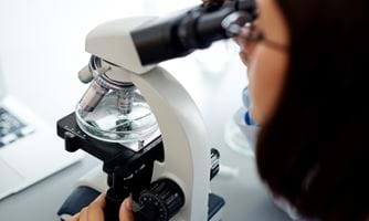 Kvinnelig mikrobiolog ser i mikroskop