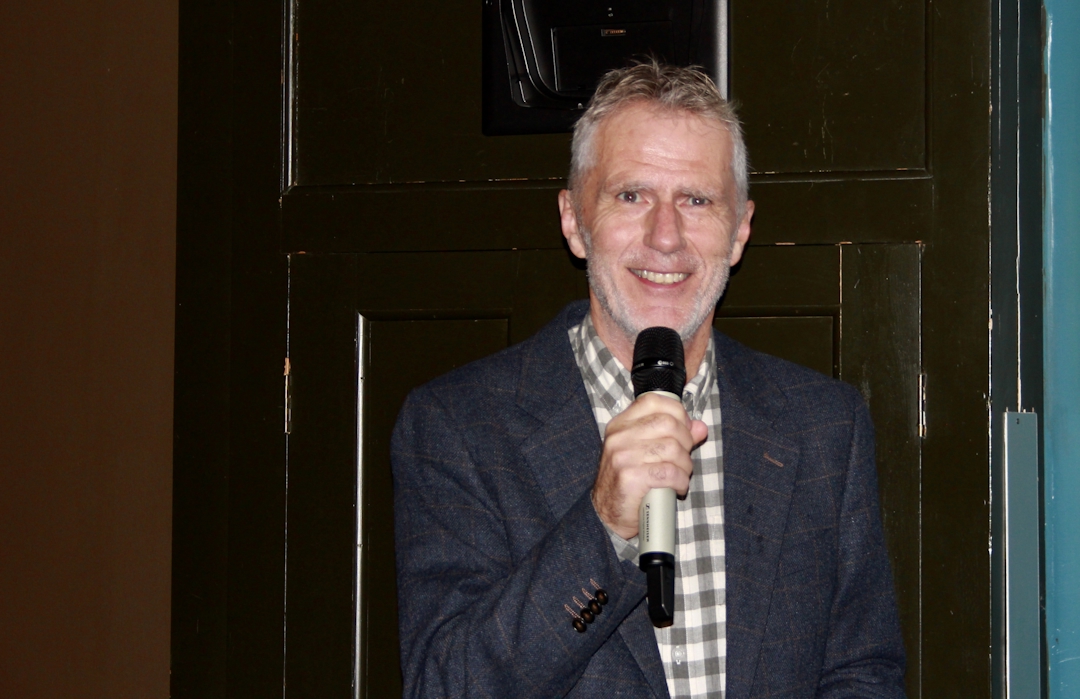 Gråhåret mann med mikrofon i hånden