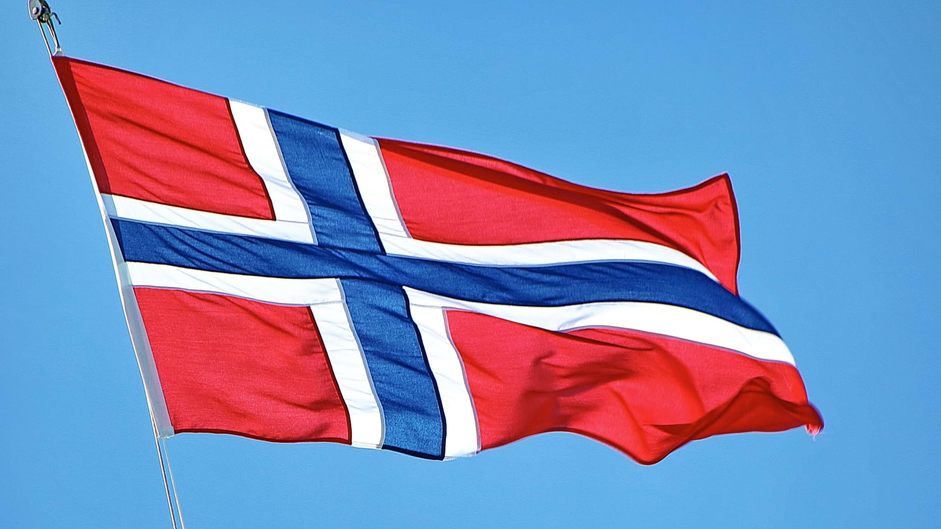 Det norske flagg som vaier i vinden. Foto: Mark K&#246;nig, Unsplash