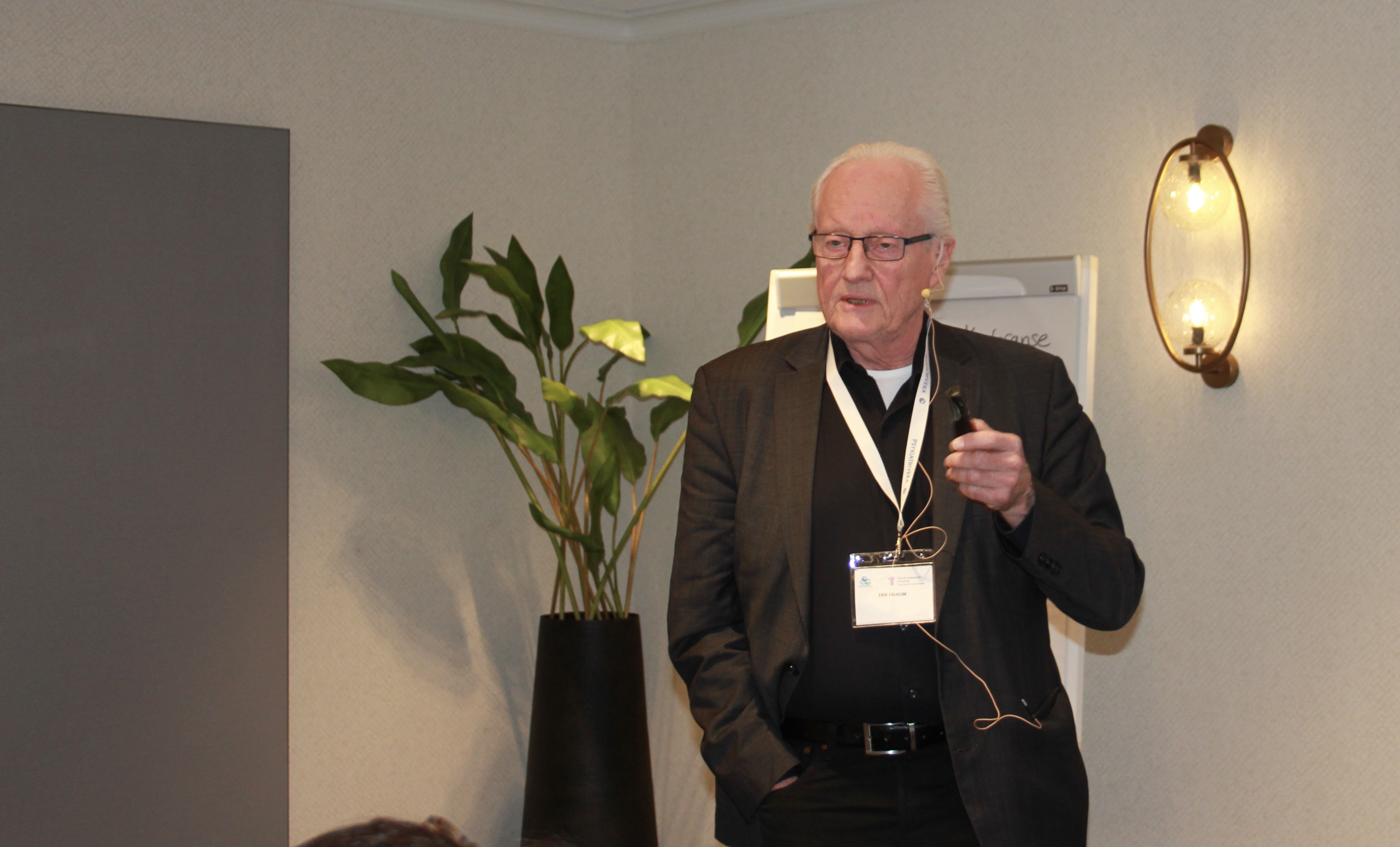 Mann i m&oslash;rk dress med lyst h&aring;r. Foreleser.