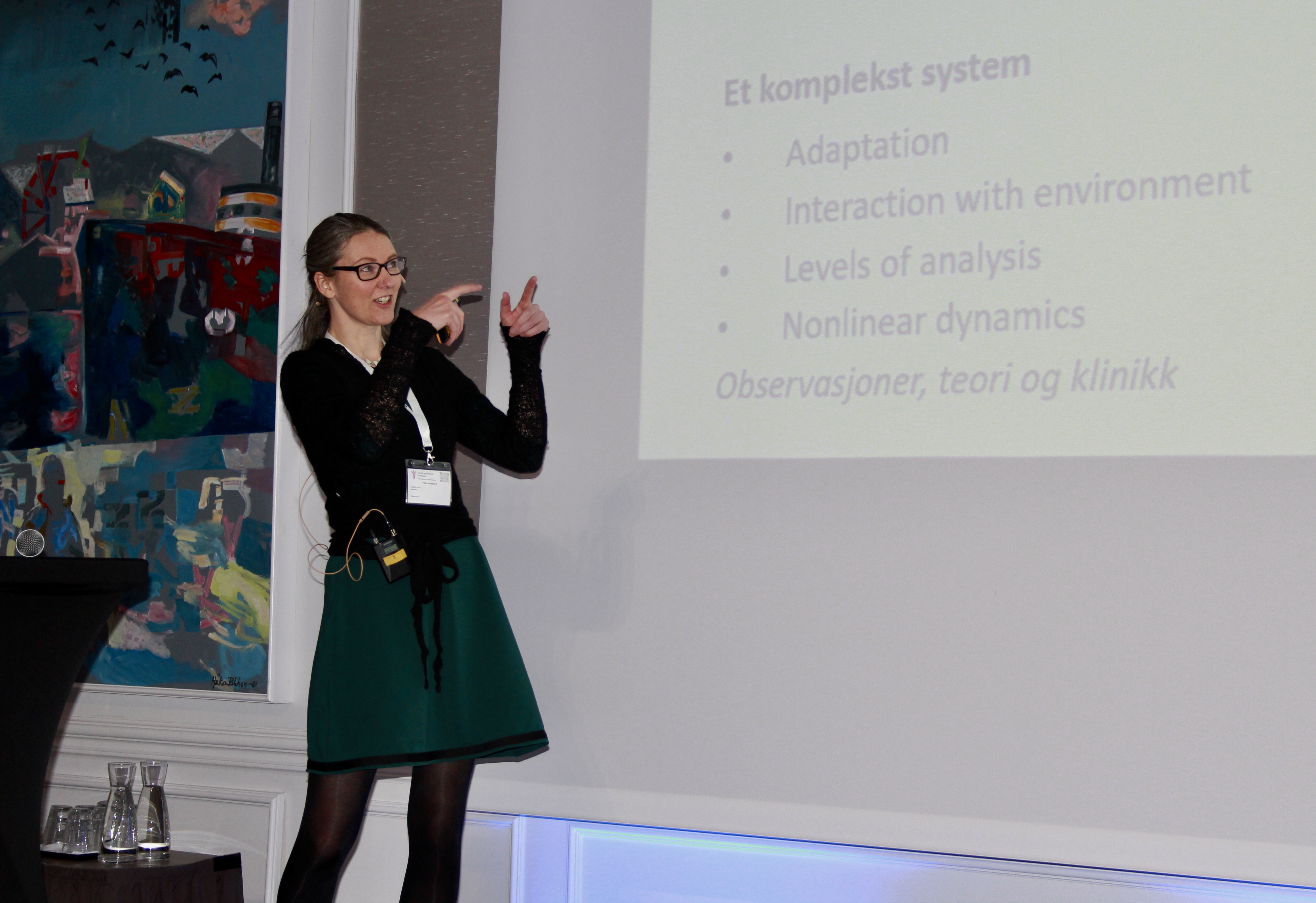 Kvinne med langt h&aring;r og kjole p&aring; et podium.