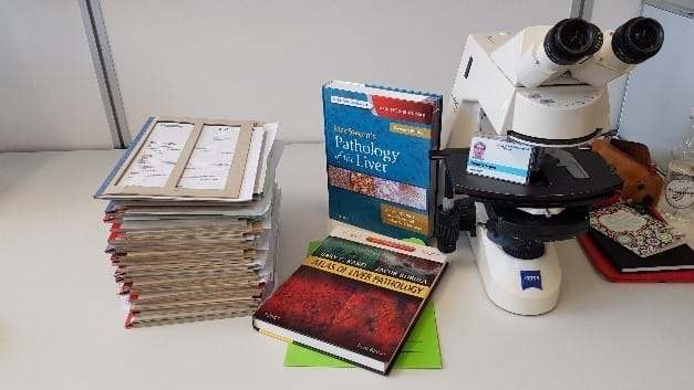 Et bord med et mikroskop og bøker om patologi - Foto: privat