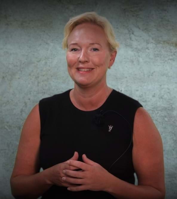 Woman presenter with hands folded in front of chest. Marte Kvittum Tangen i Noklus video.