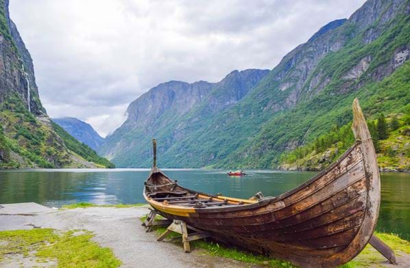 Vikingbåt på land ved Gudvangen, med fjorden i bakgrunnen. Foto: Istockphoto.com Fotograf:Jana_Janina