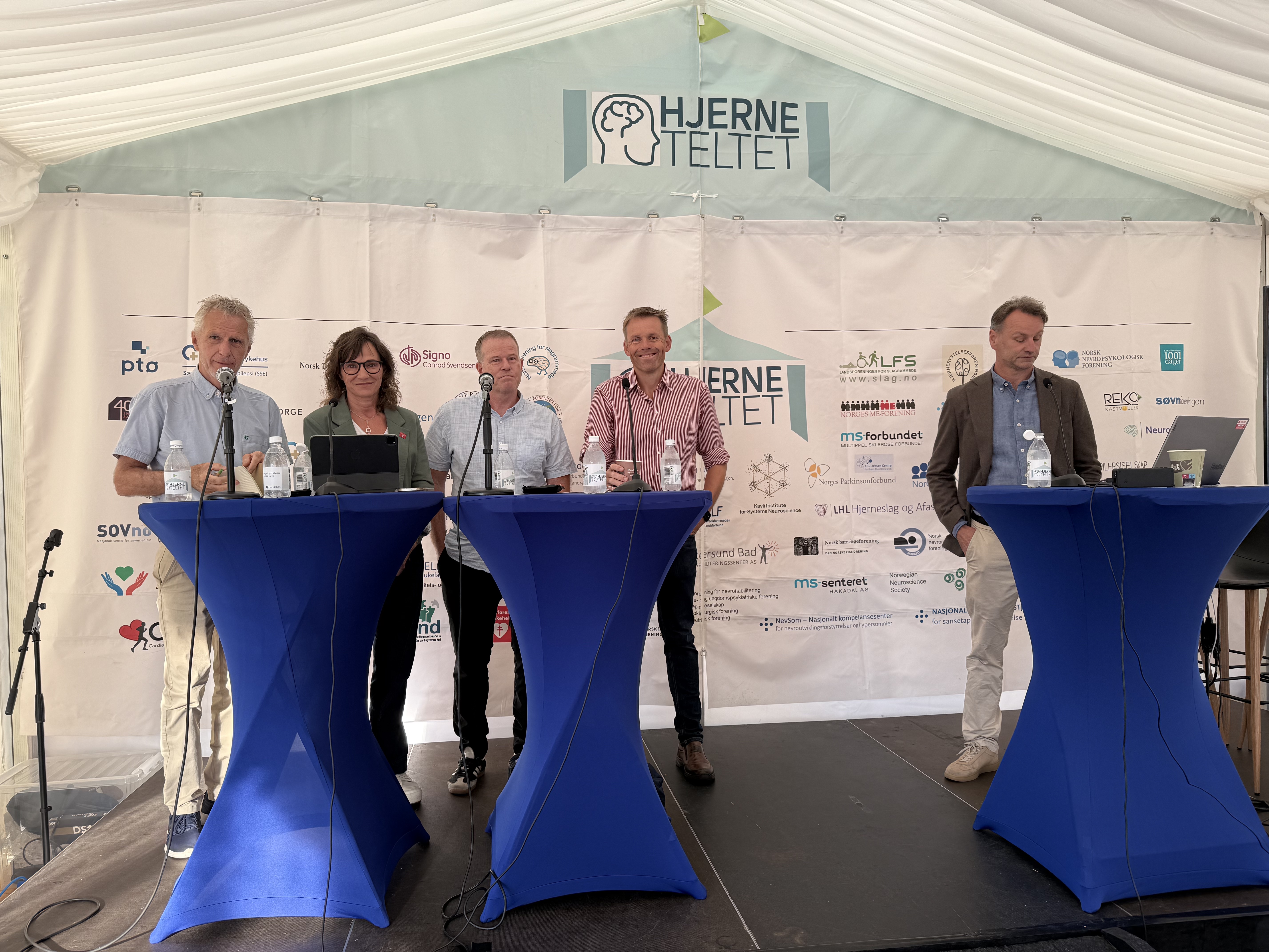 En rekke mennesker p&aring; en scene, talerstol.