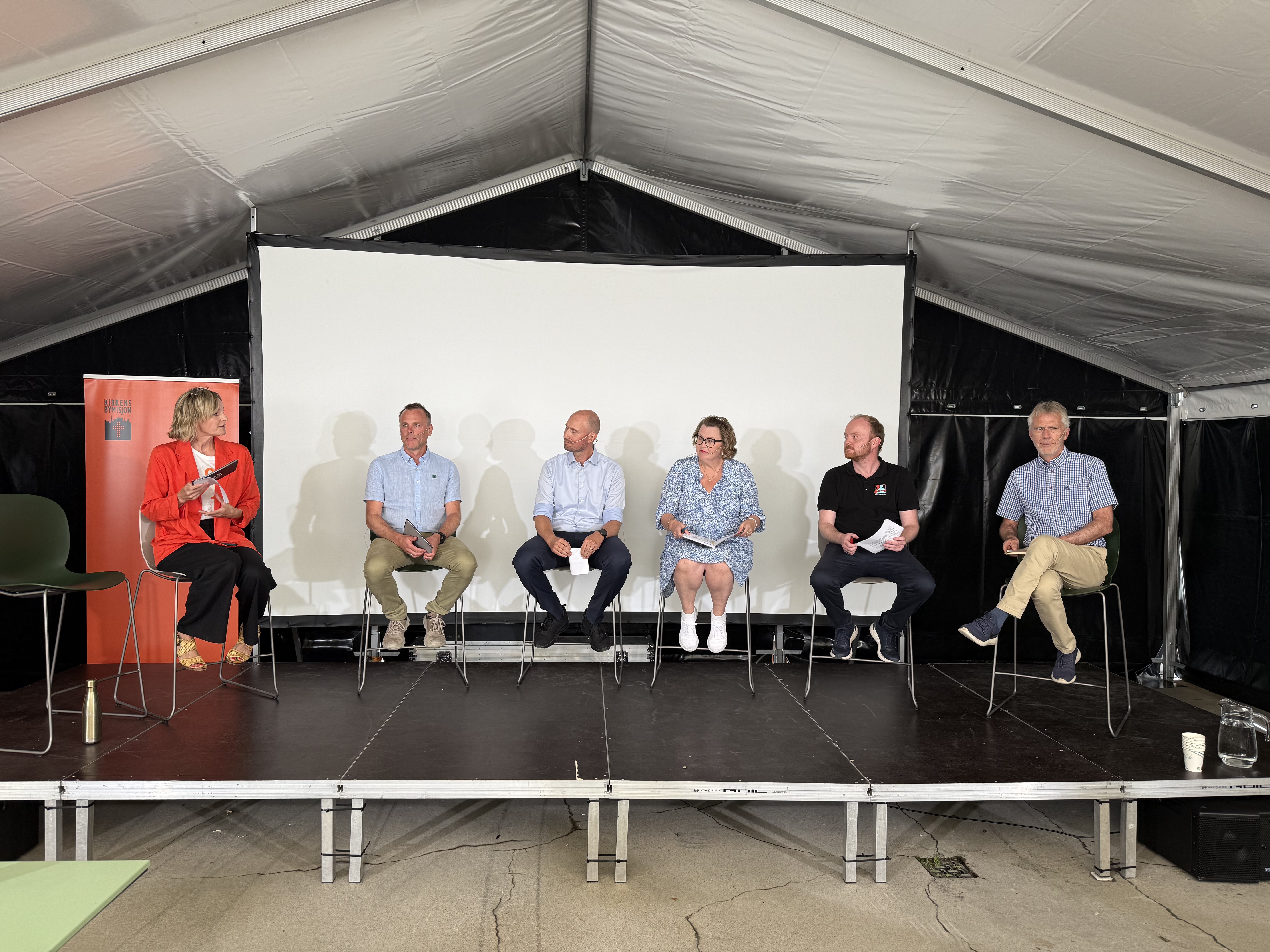 En rekke med mennesker p&aring; barstoler p&aring; en scene.