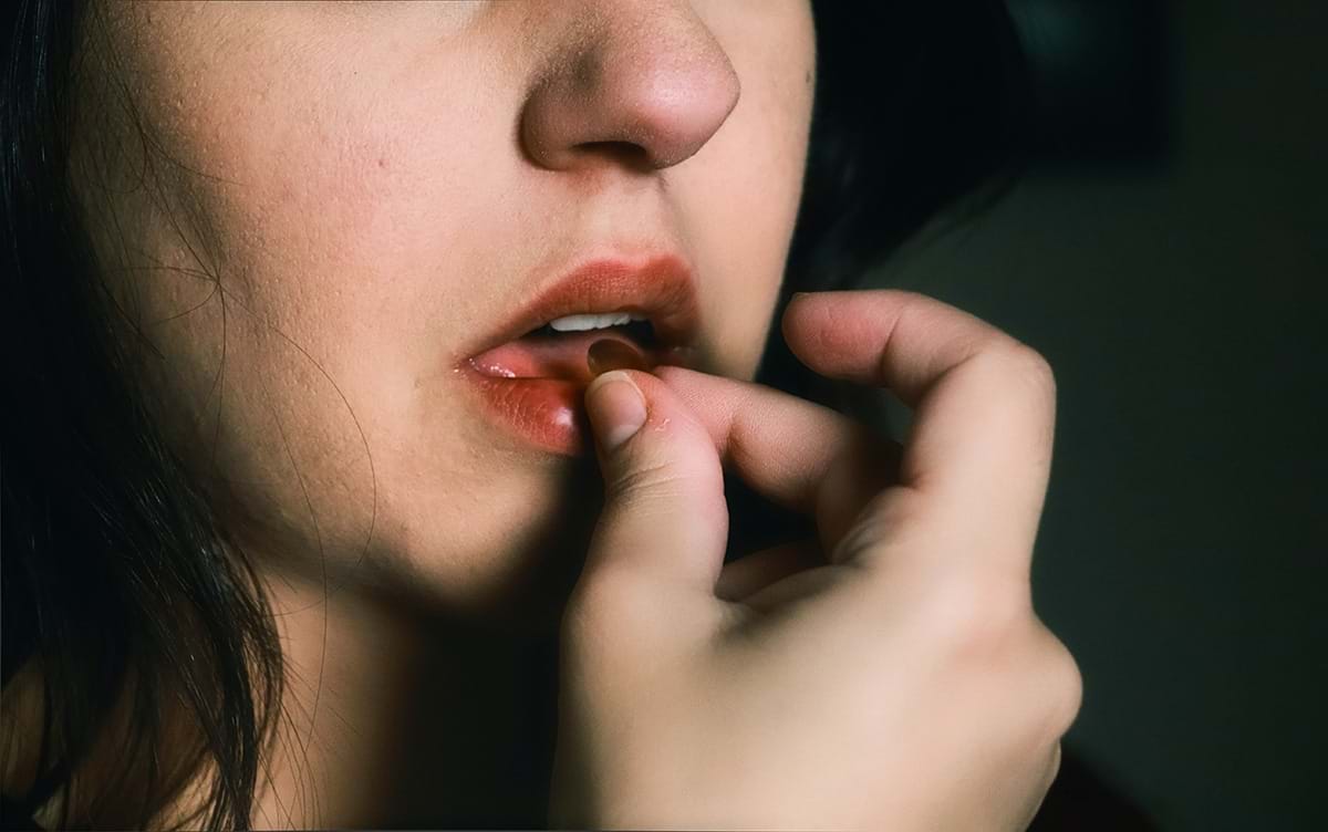 En kvinne som tar seg en pille. Foto: Unsplash.com