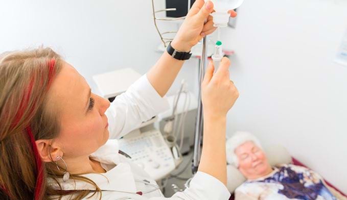 Kvinnelig lege gir pensjonist i dryppinfusjon på sykehus.