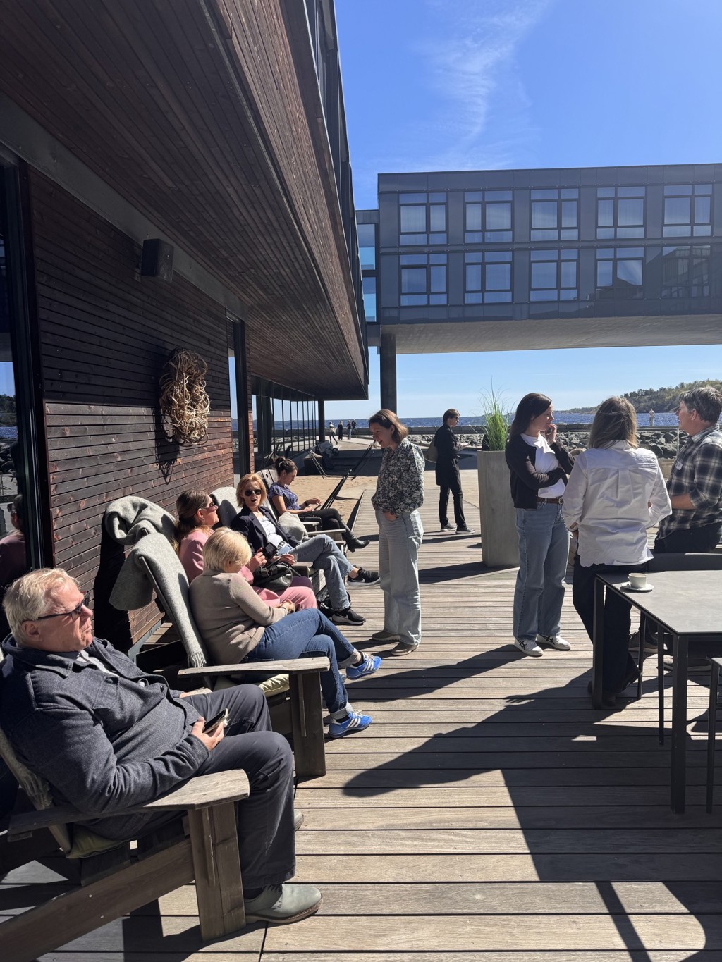 Folk sitter i solveggen utenfor Farris bad