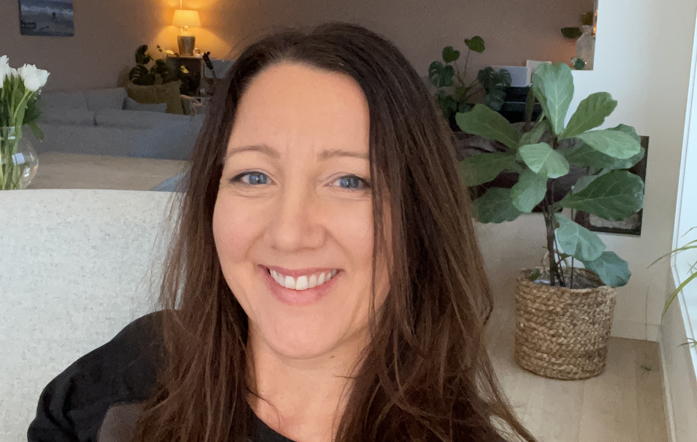 Kvinne,  smilende, langt brunt h&aring;r. Stue i bakgrunnen