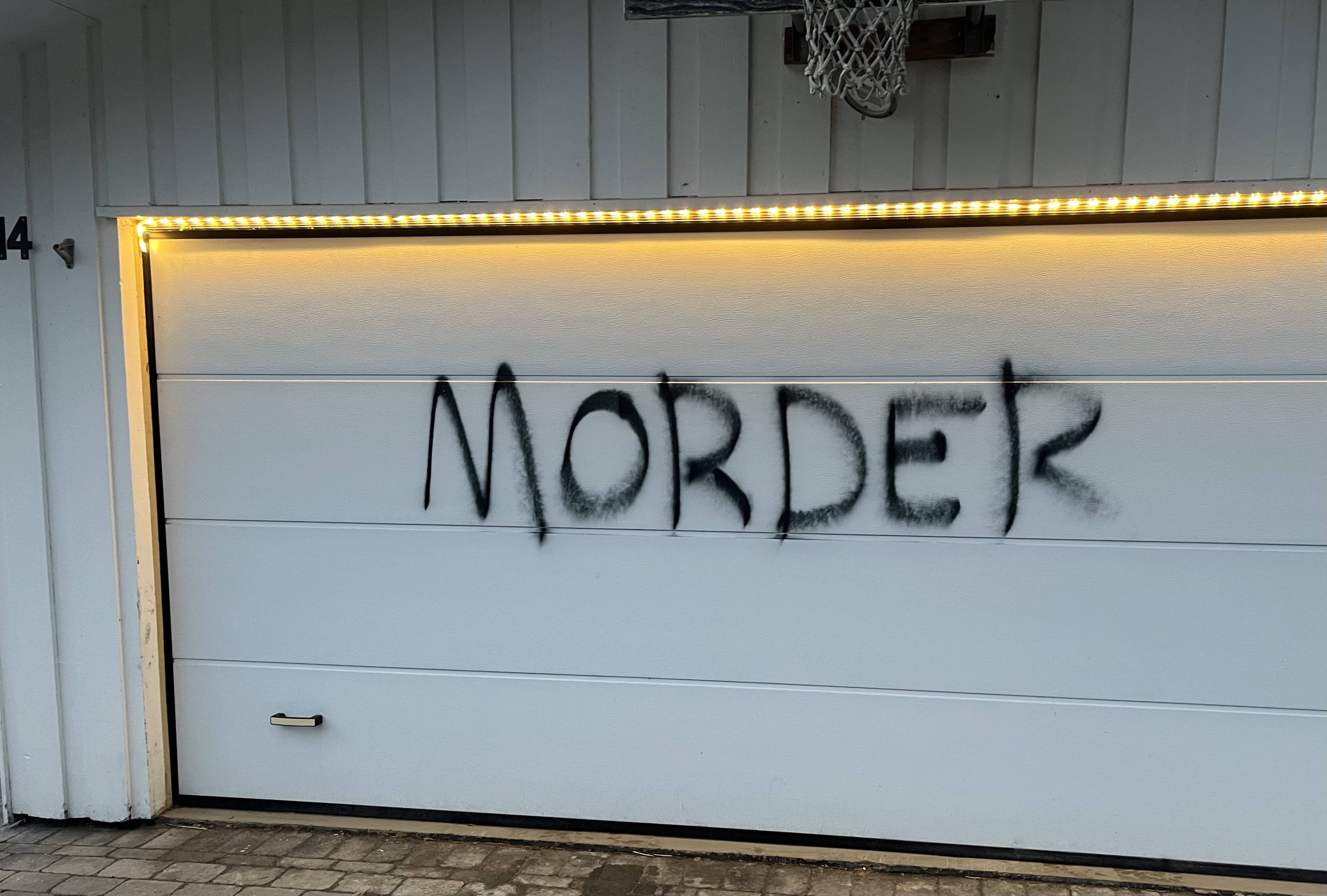 Hvit garasjeport med svart skrift i spraymaling