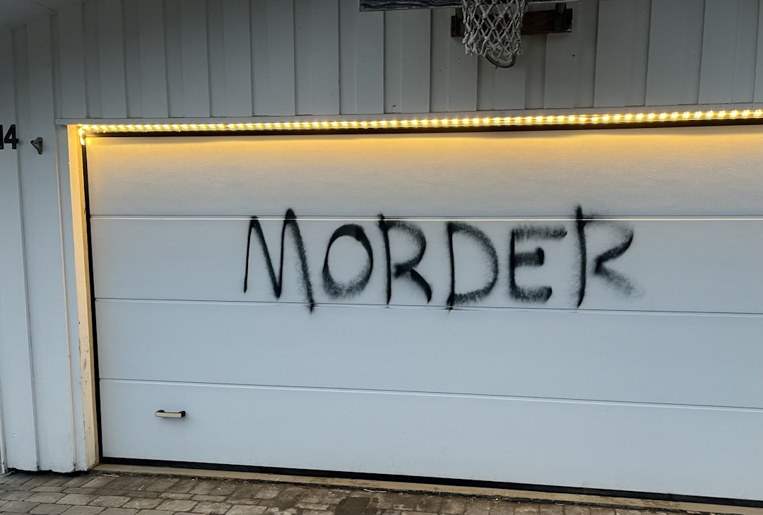 Hvit garasjeport med svart skrift i spraymaling