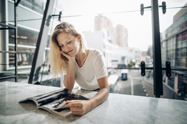 Kvinne som sitter ved et bord og leser et magasin. Foto: Istockphoto.com/SolStock