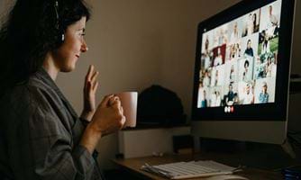 En kvinne med en kaffkopp som sitter foran en datamaskin med et digitalt møte. Foto: Istockphoto.com