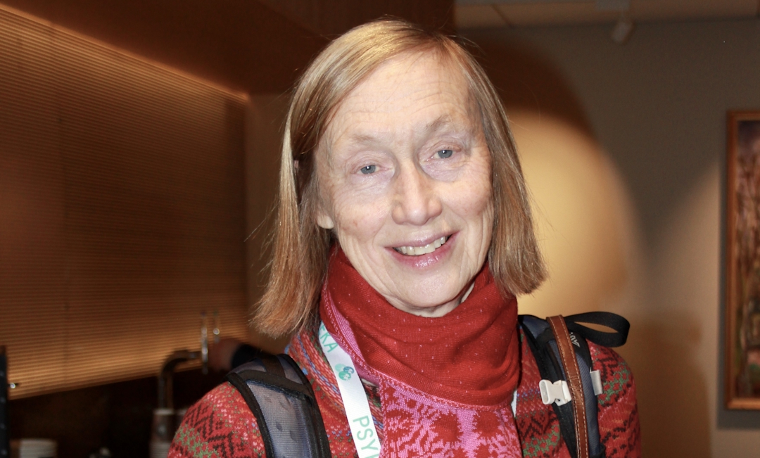 Smilende kvinne med lyst hår og fargerike klær.