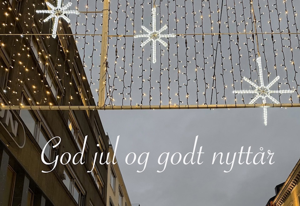 En gate i Oslo med lyspynt og stjerner. Grå himmel. Noen bygninger på sidene.
