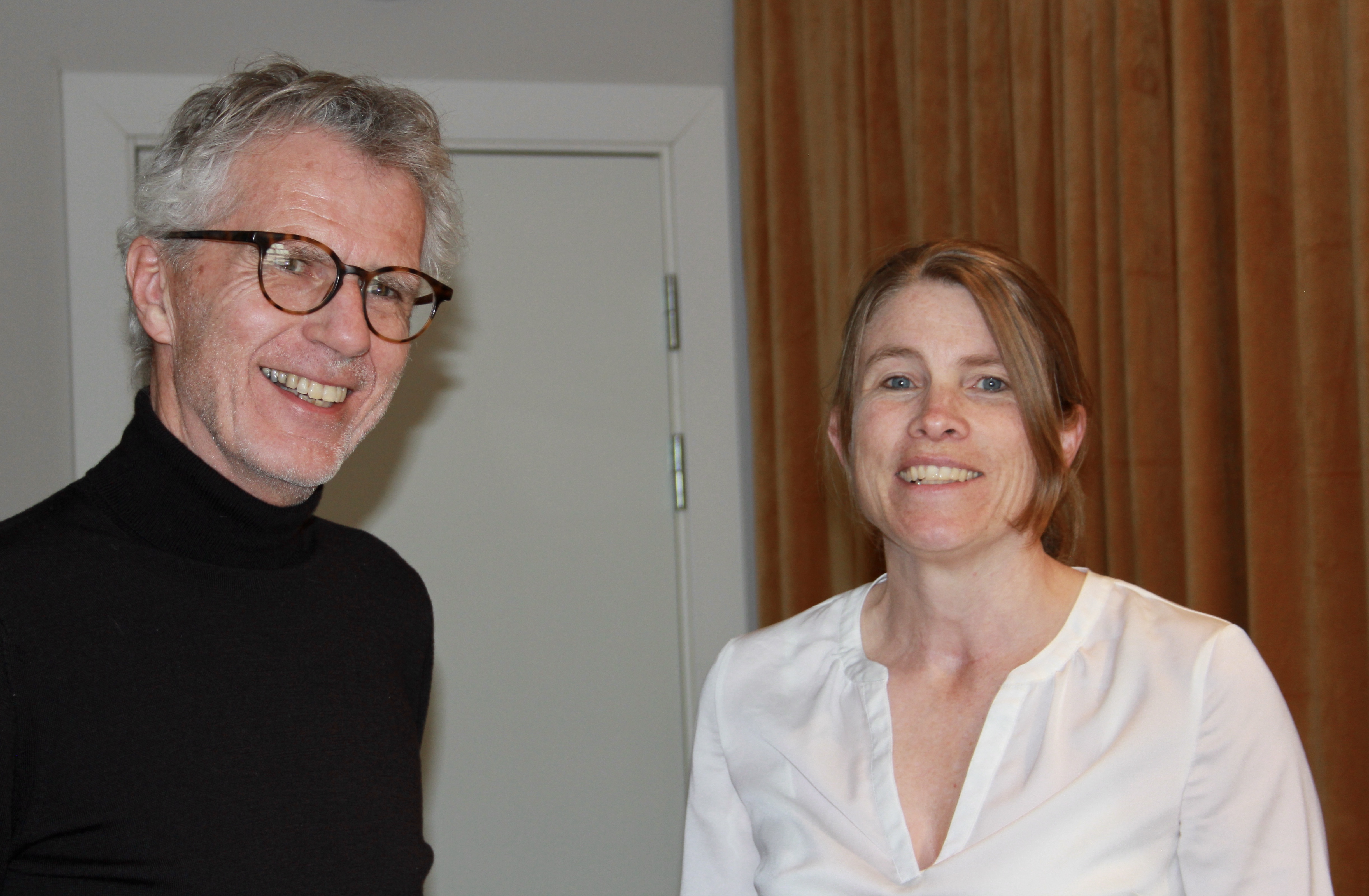 En mann med gr&aring;tt h&aring;r og svart genser. En kvinne med blondt h&aring;r og hvit bluse.