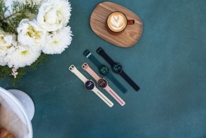 Fire stykk Vivoactive 6 liggende ved siden av en kopp kaffe. Foto: Garmin