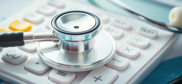 Stetoskop liggende på en kalkulator. Foto: Istockphoto.com/erdikocak