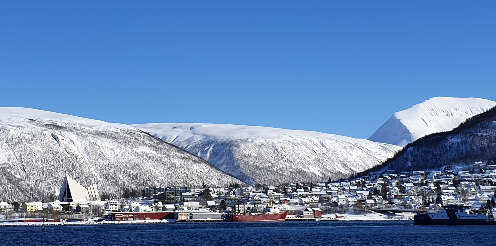 Troms&#248; by og fjell med bl&#229; himmel. Foto: Lars Gustav Lyckander