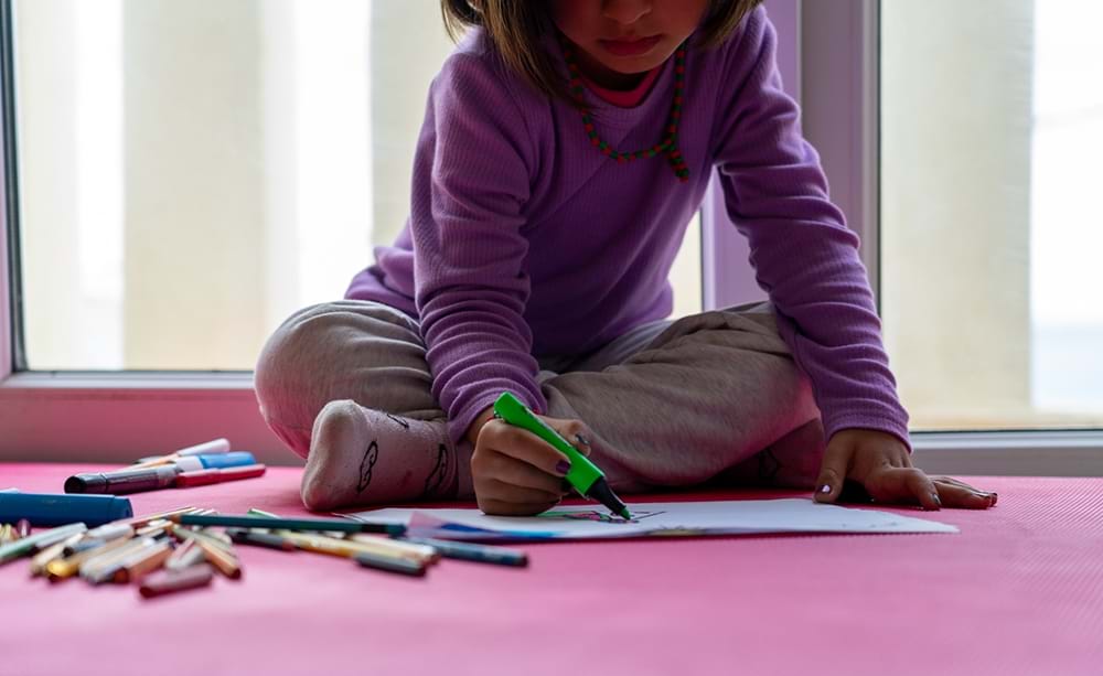 Et barn tegner mens hennes mor deltar i en sesjon som handler om helsefremmende arbeid i regi av Leger uten grenser p&#229; en klinikk p&#229; Lesvos.