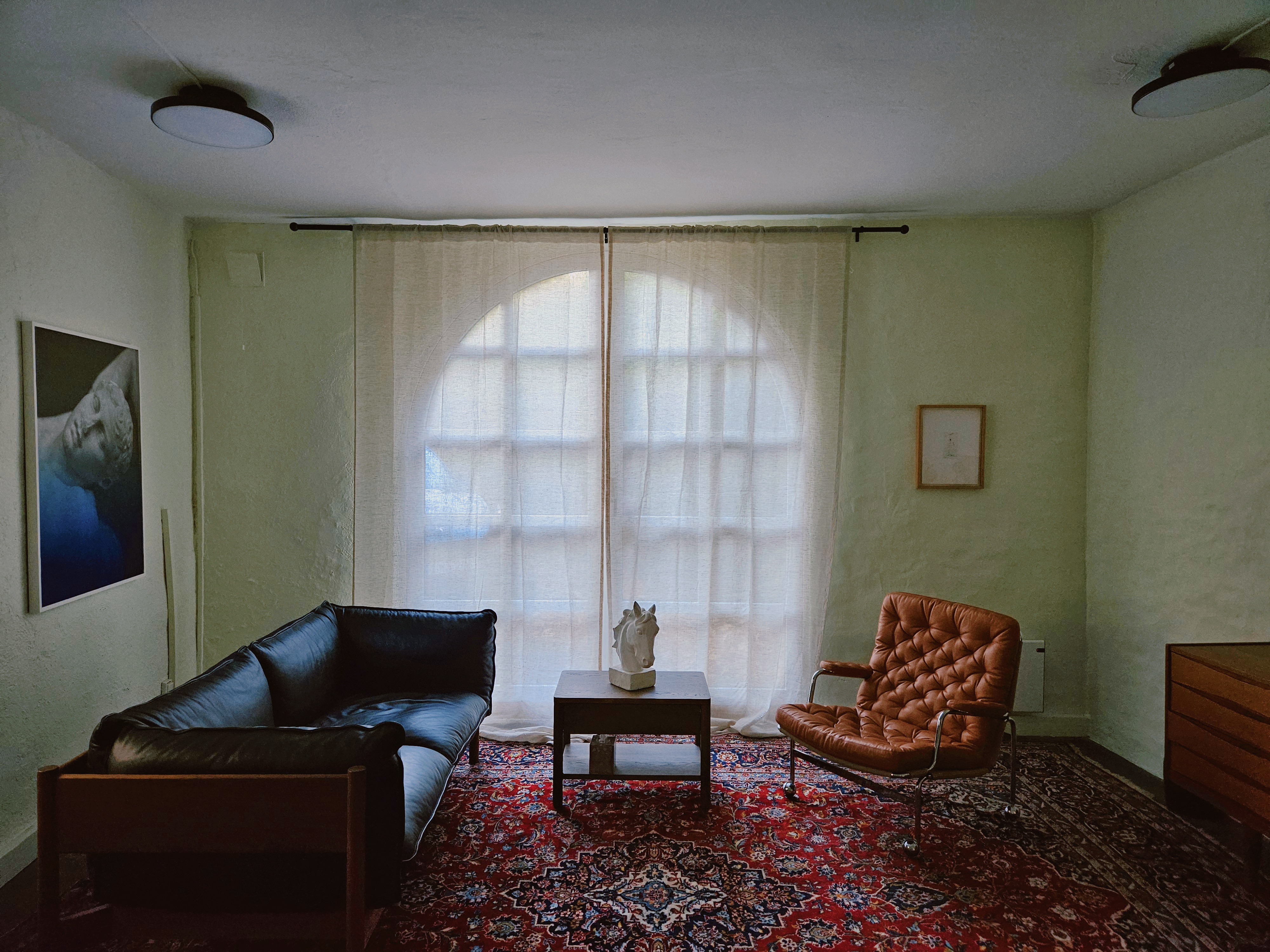 Et kontor med stort vindu, teppe p&aring; gulvet. m&oslash;bler.