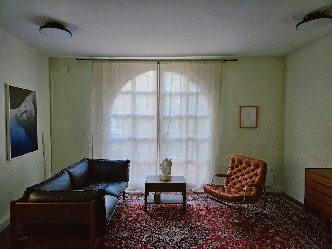 Et kontor med stort vindu, teppe på gulvet. møbler.