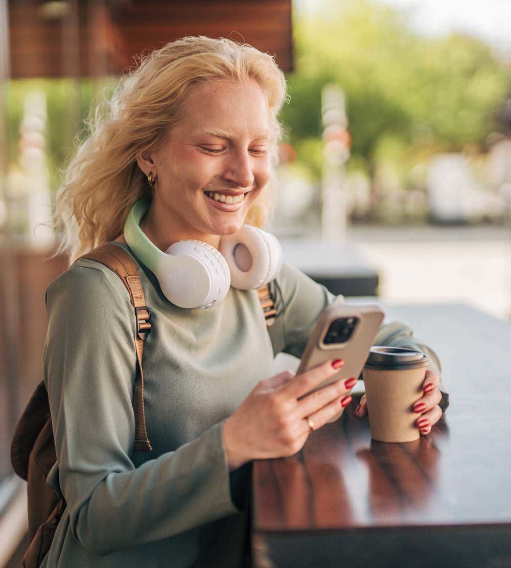 En kvinne som drikker kaffe og ser på mobiltelefonen. Foto: Akademikerne pluss