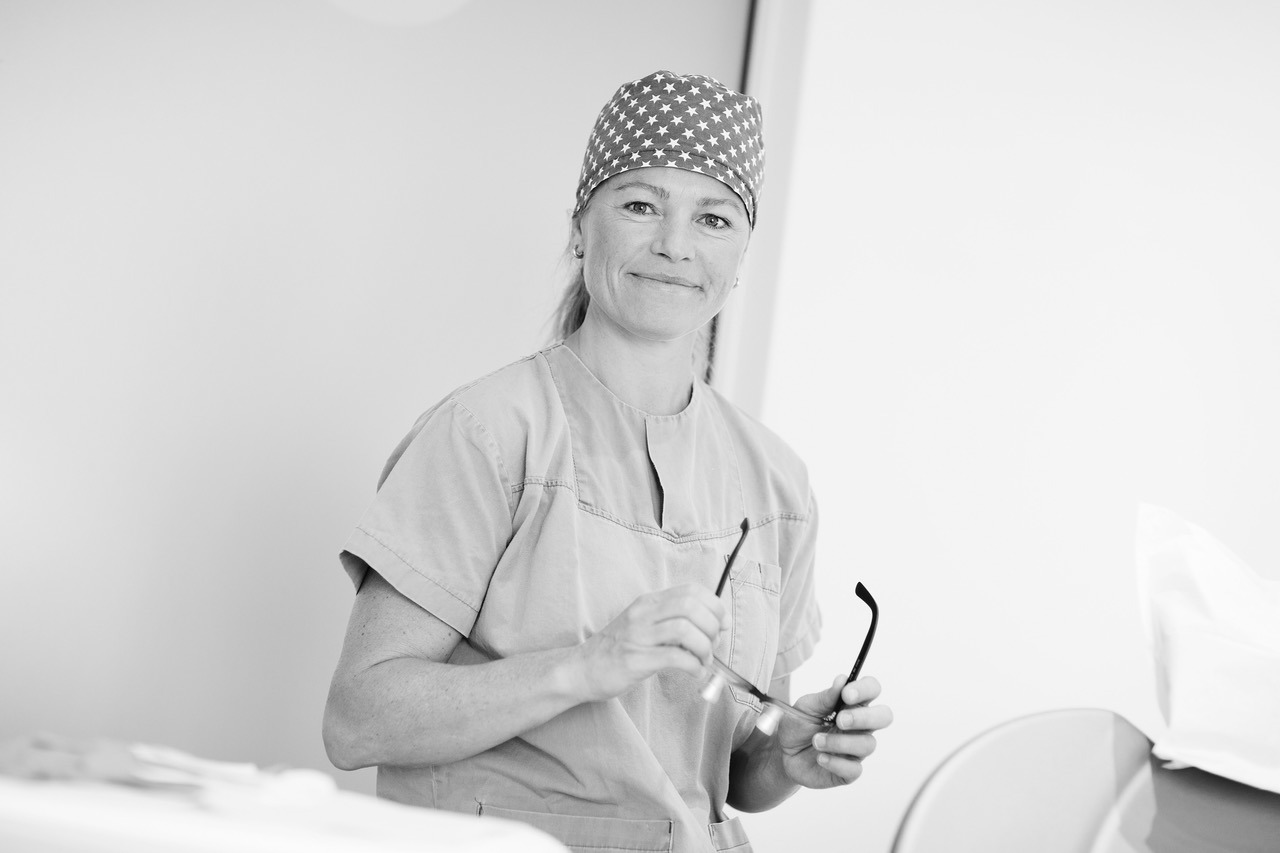 Bilde av en kvinne i klinikktøy på et tannlegekontor.