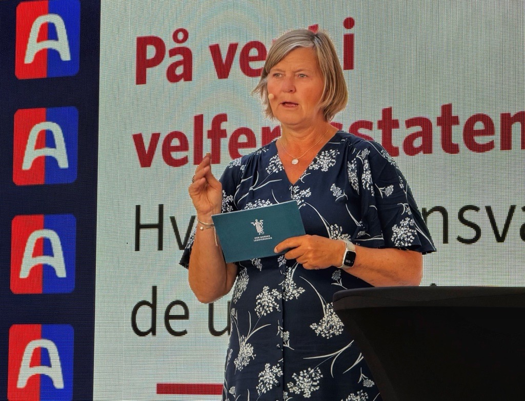 Anne-Karin Rime står på en scene og holder innlegg foran en storskjerm med teksten «På vent i velferdsstaten». Rime holder telekort i hånden.