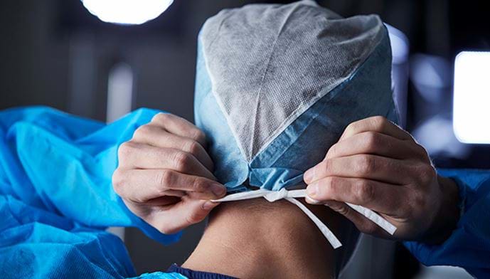 Bilde av kirurg som binder kirurgisk hette under forberedelse, bakfra