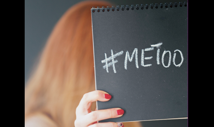 En kvinne viser frem påskriften #Metoo på en skriveblokk