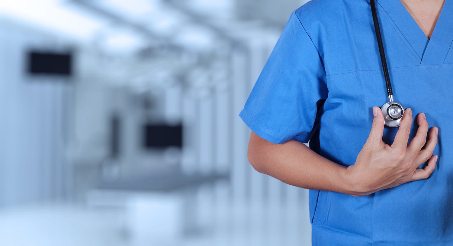 Nærbilde av overkropp til lege i blå skjorte med stetoskop hengende rundt halsen. Foto: Colourbox. 